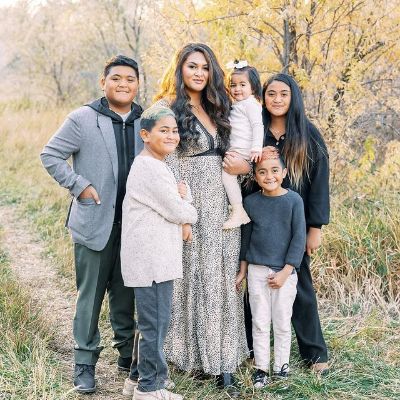 Alayna Finau is carrying Sienna-Vee and other kids have surrounded her.